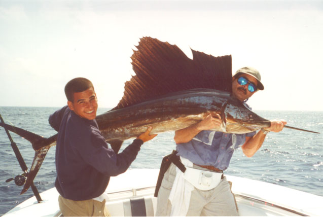 photo of A.J.Ribas and his father, Alberto, with 100 lb. sail caught on a pilchard fished below a kite over Fowey Rocks (off Miami) and released in good shape